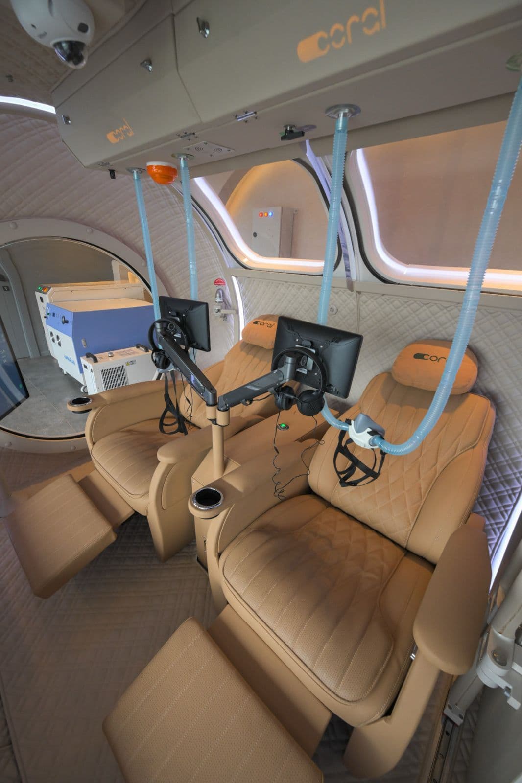 Coral Ark cabin detail, reclining leather seats with oxygen masks and the control monitor on its articulated arm